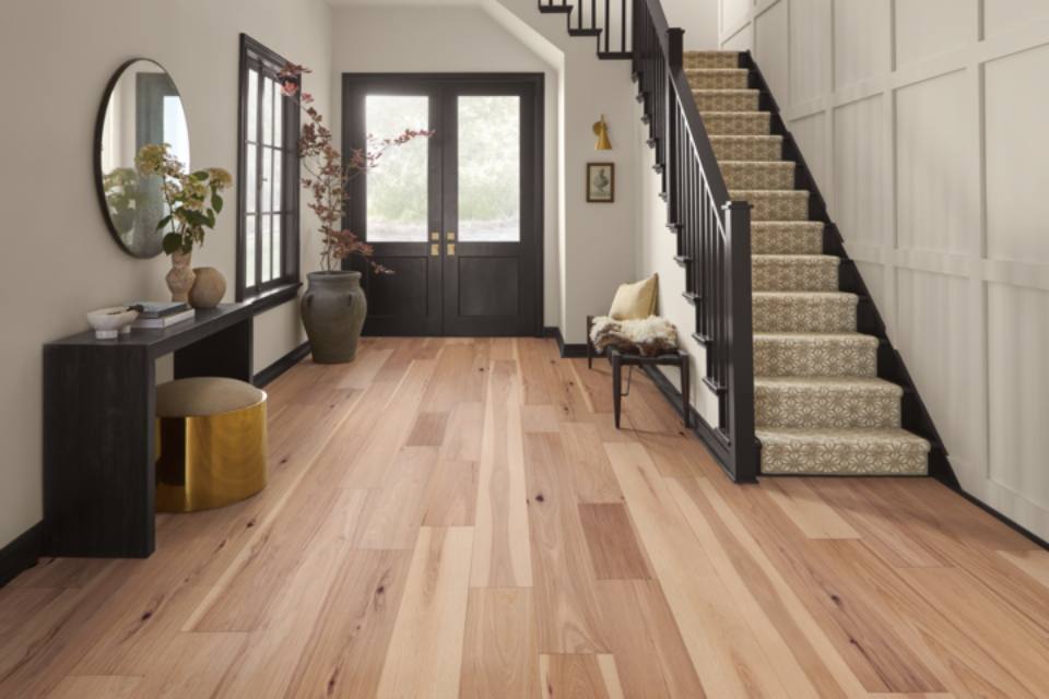 warm toned hardwood flooring in entryway with dark wood accent furniture.